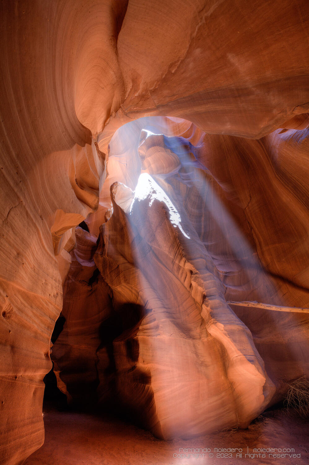 Sunlight piercing through narrow sandstone walls inside Antelope Canyon, Arizona, USA, creating dramatic beams of light and shadow across the curved rock formations