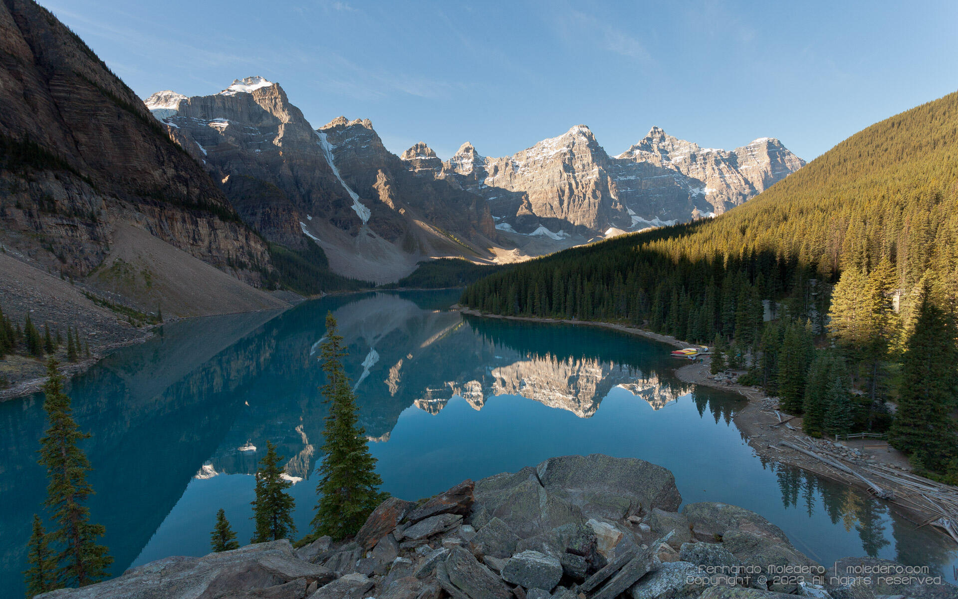 Scenic view of Moraine Lake in Banff National Park, Alberta, Canada, with turquoise water reflecting the Valley of the Ten Peaks and surrounding pine forests under a clear sky